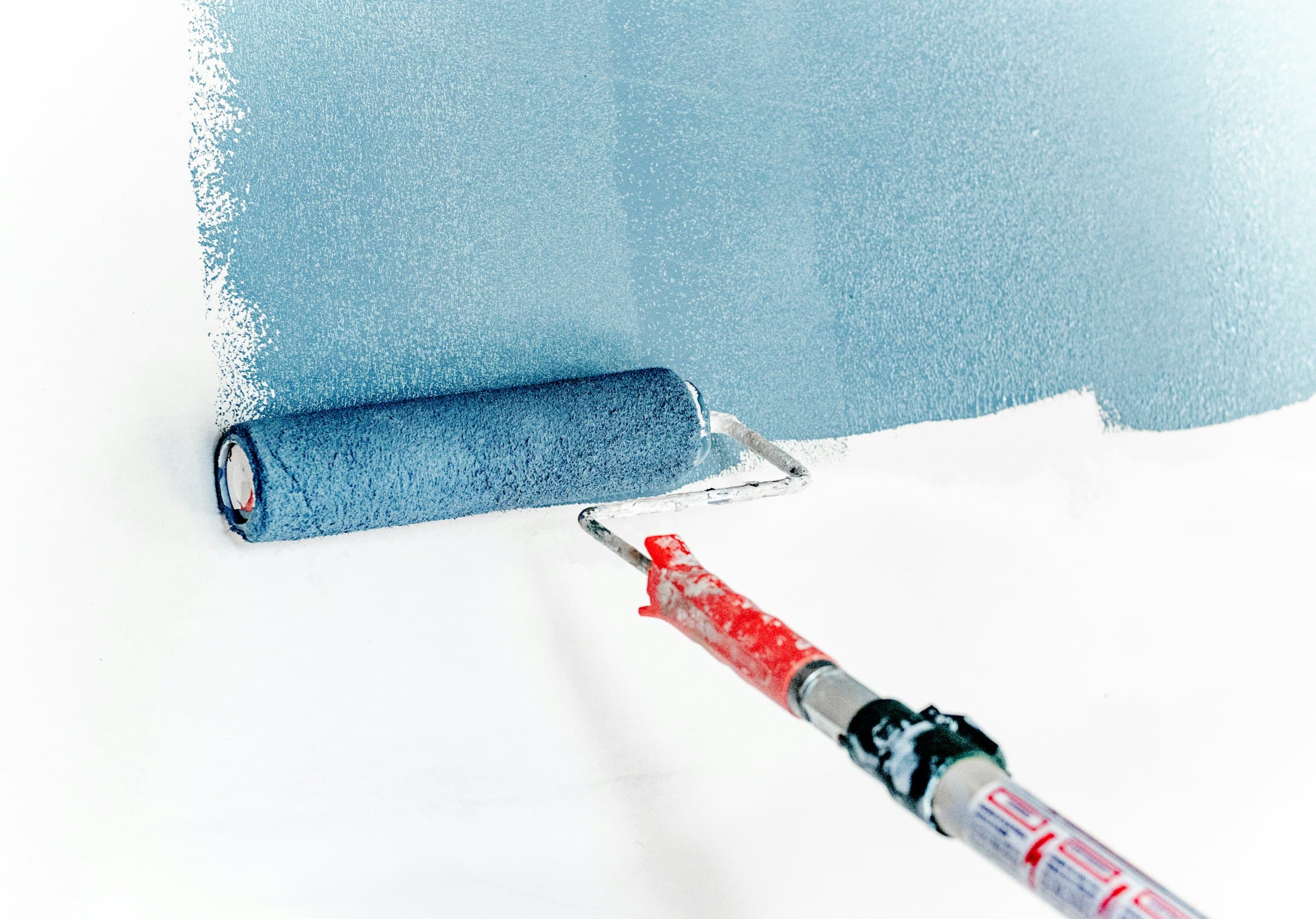 Decorator painting a wall with a roller in a fresh blue