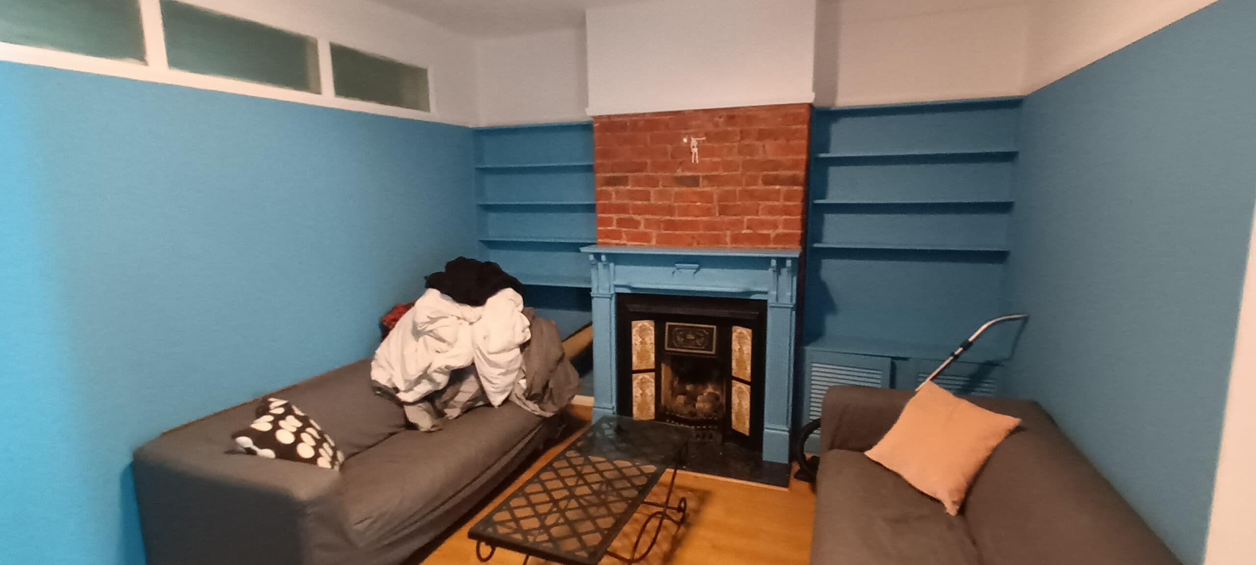Refurbished living room with built-in shelving and a restored fireplace by HandyMack